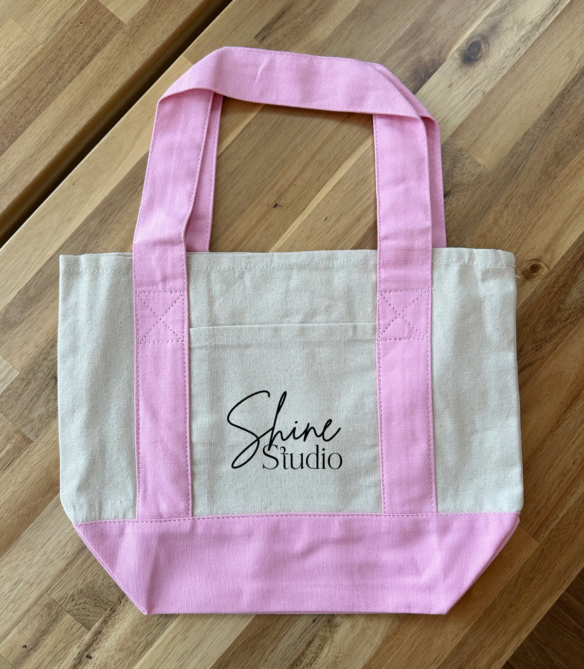 Small canvas tote bag with pink handles and a custom printed logo for business gifts and promotional events.
